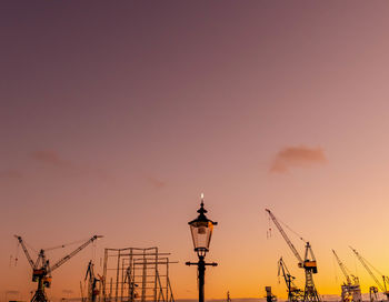 Silhouette of street lights against orange sky