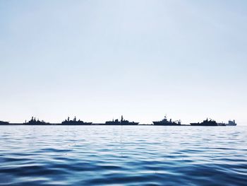 Boats sailing in sea against clear sky