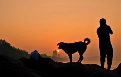 Silhouette men standing on mountain during sunset