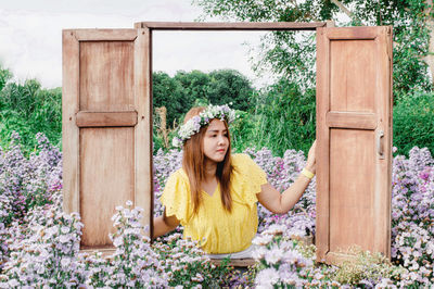 Young woman looking at camera while standing against plants