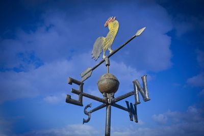 Low angle view of weather vane against blue sky