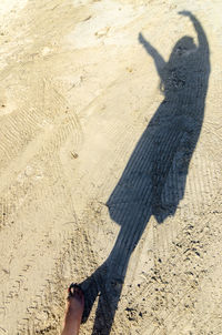 Shadow of woman on sand during sunny day