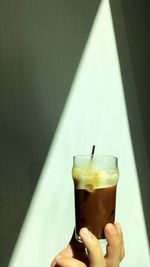 Midsection of person holding drink against wall