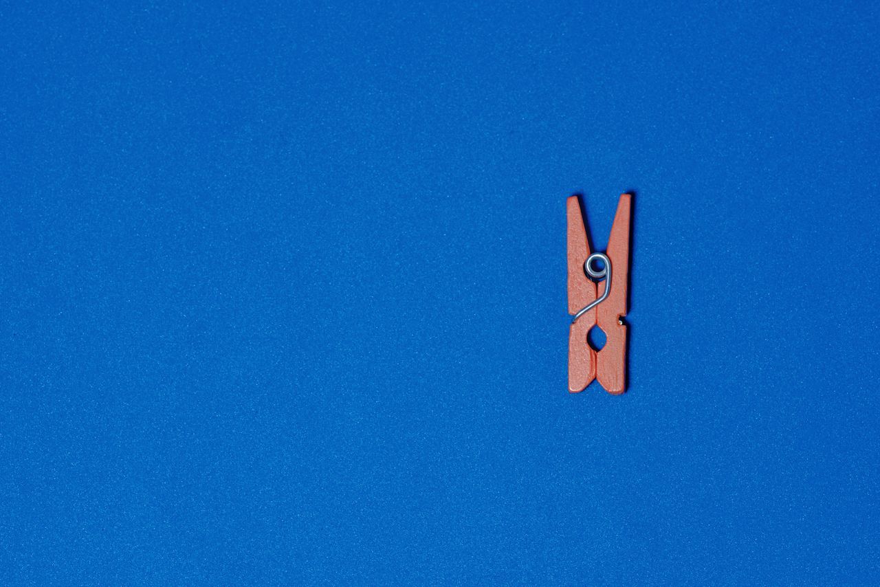 LOW ANGLE VIEW OF CLOTHESPINS ON BLUE SKY AGAINST CLEAR BACKGROUND