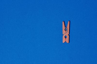 Low angle view of clothespins on blue sky