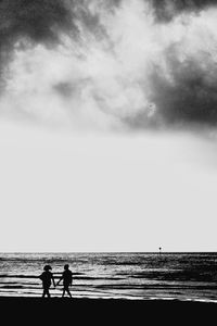 Silhouette people on beach against sky