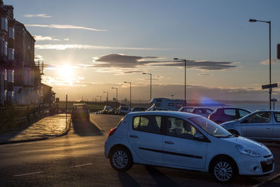 Cars on road against sky during sunset