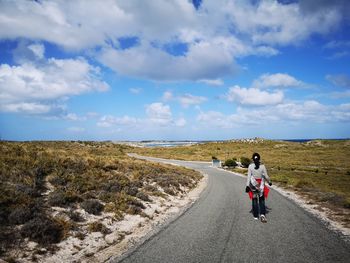 Rear view of woman riding motorcycle on road against sky