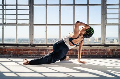 Full length of woman exercising by window