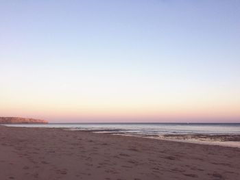 Scenic view of beach against clear sky during sunset