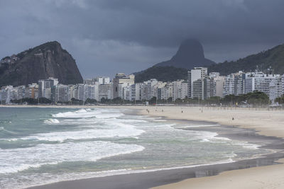 Scenic view of beach by city against sky