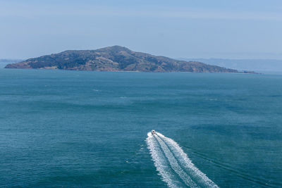 Scenic view of sea by mountain against sky