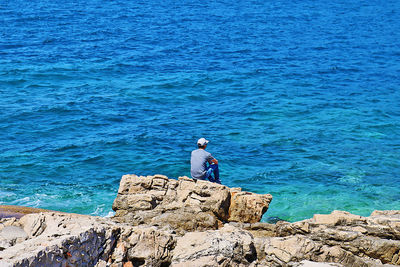 Man standing on rock by sea