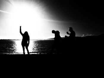 Silhouette people on beach against sky