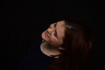 Portrait of a smiling young woman against black background