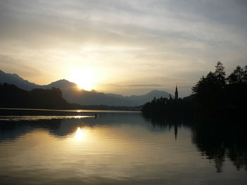 Scenic view of lake against cloudy sky at sunset