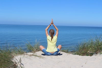 Full length of senior woman in sea against sky yoga meditation