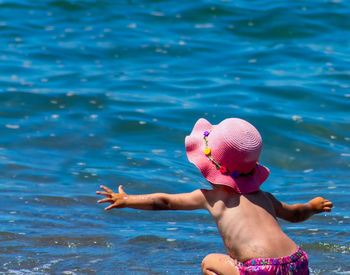 Rear view of girl playing on shore at beach