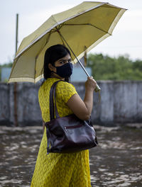 An indian woman in yellow dress and face mask on is going outside after unlock 1.0 of corona virus