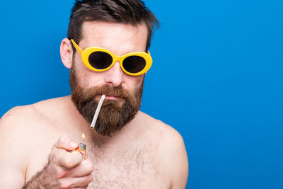 Portrait of man wearing sunglasses against blue background