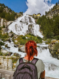 Rear view of woman on waterfall against mountain