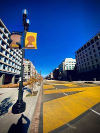 Road amidst buildings against blue sky