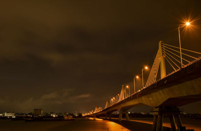 Bridge over illuminated city against sky at night
