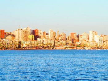 Sea by buildings against clear blue sky