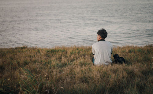 Rear view of woman with dog sitting on shore