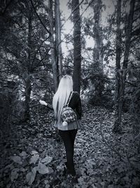 Rear view of woman standing in forest