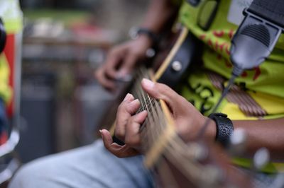 Midsection of man playing guitar