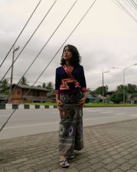 Young woman standing against sky