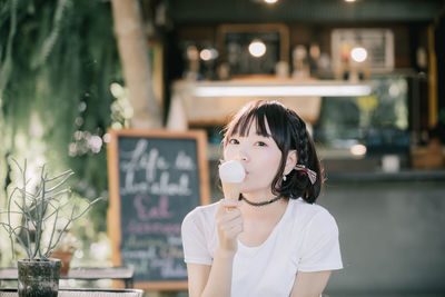 Portrait of young woman eating ice cream at restaurant