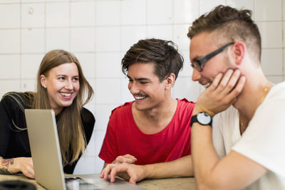 Happy young business people using laptop in creative office