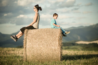 Young couple standing on field against sky