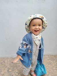 Portrait of cute baby girl standing against wall