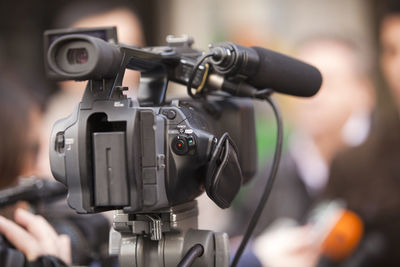 Close-up of television camera with people in background