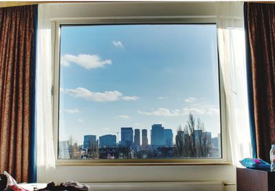 Buildings against sky seen through glass window