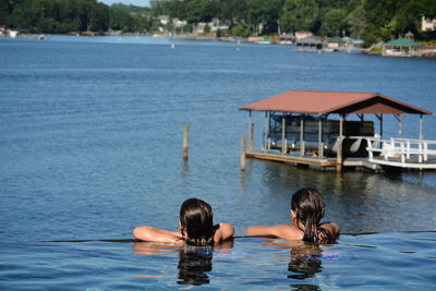 Rear view of sisters swimming in infinity pool by lake norman 