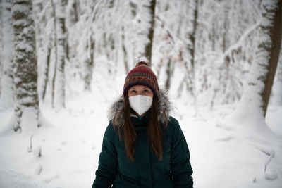 Portrait of woman standing on snow covered field during winter