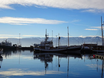 Fishing boats in harbor at lake against sky