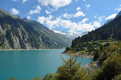 Scenic view of river by mountains against sky