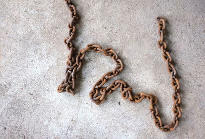 
an old chain rusted on the cement floor.