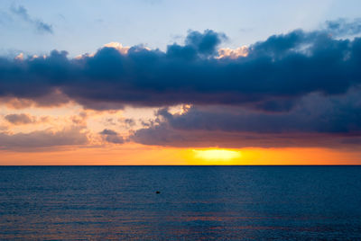 Scenic view of sea against cloudy sky during sunset