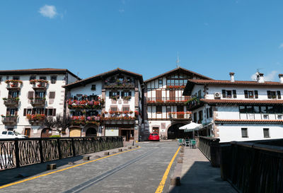 Road by buildings against clear sky in city