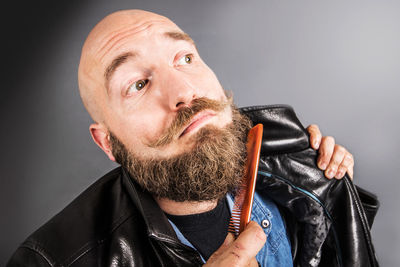 Man combing beard against gray background