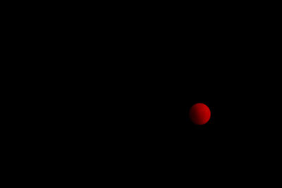 Low angle view of red moon against sky at night
