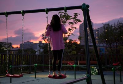 Rear view of girl against sky during sunset