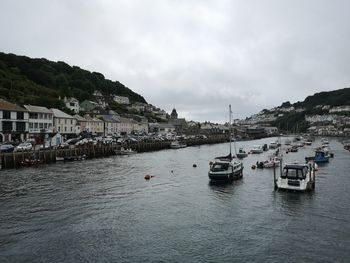 Sailboats in sea by buildings against sky