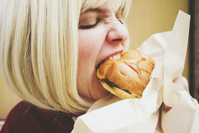 Woman with blond hair eating hamburger